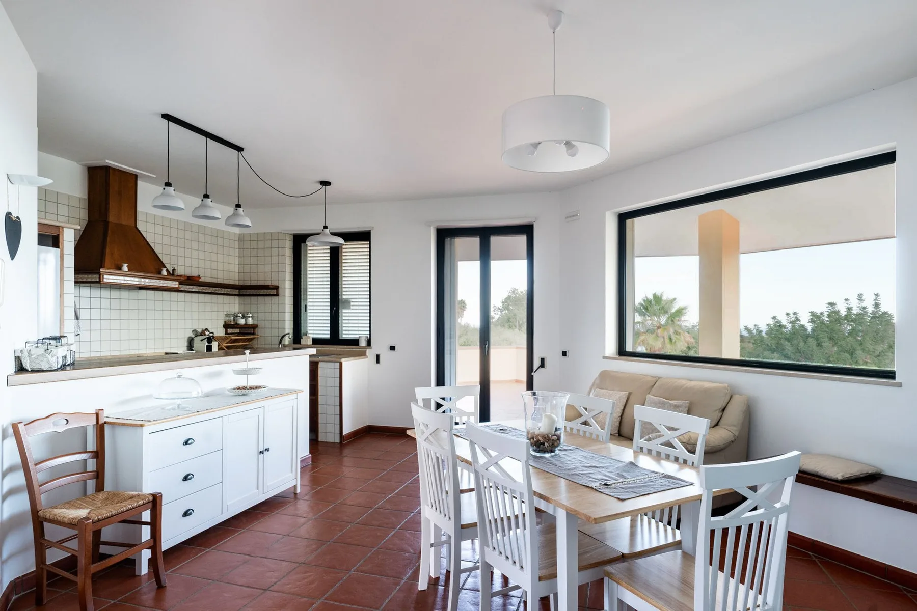 Cocina abierta y comedor con una mesa junto a una ventana amplia.