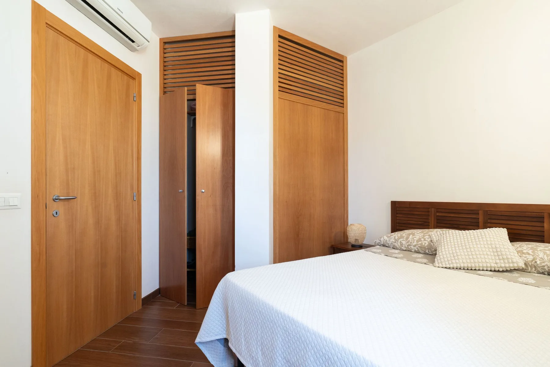 Un dormitorio con una cama bien hecha y puertas de madera.