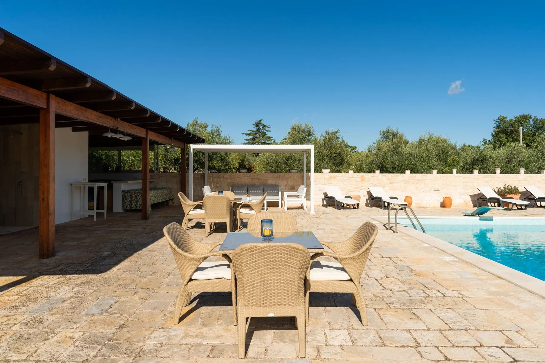 Un patio soleado con piscina, asientos y tumbonas.