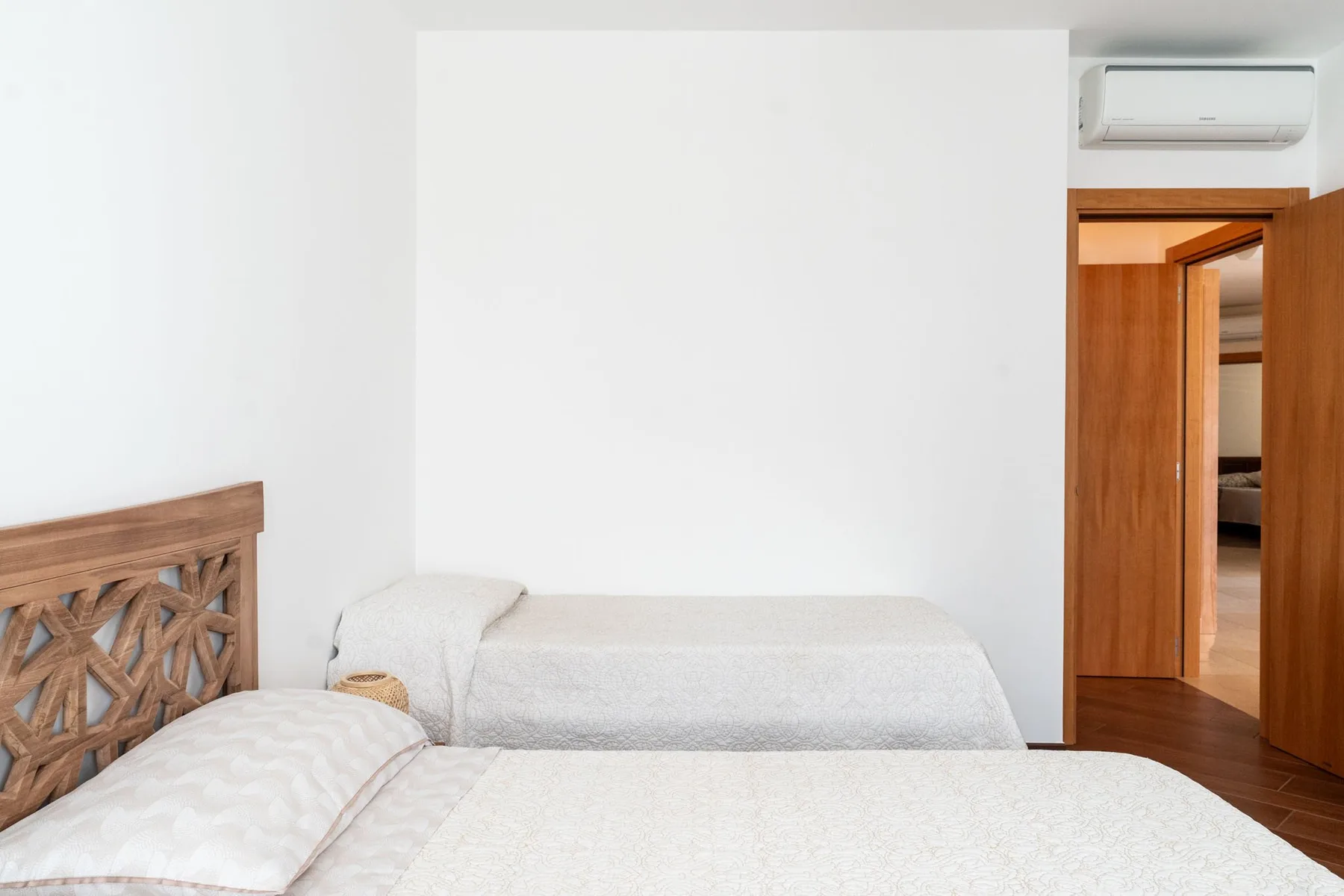 Un dormitorio con camas, un cabecero de madera y una puerta abierta.