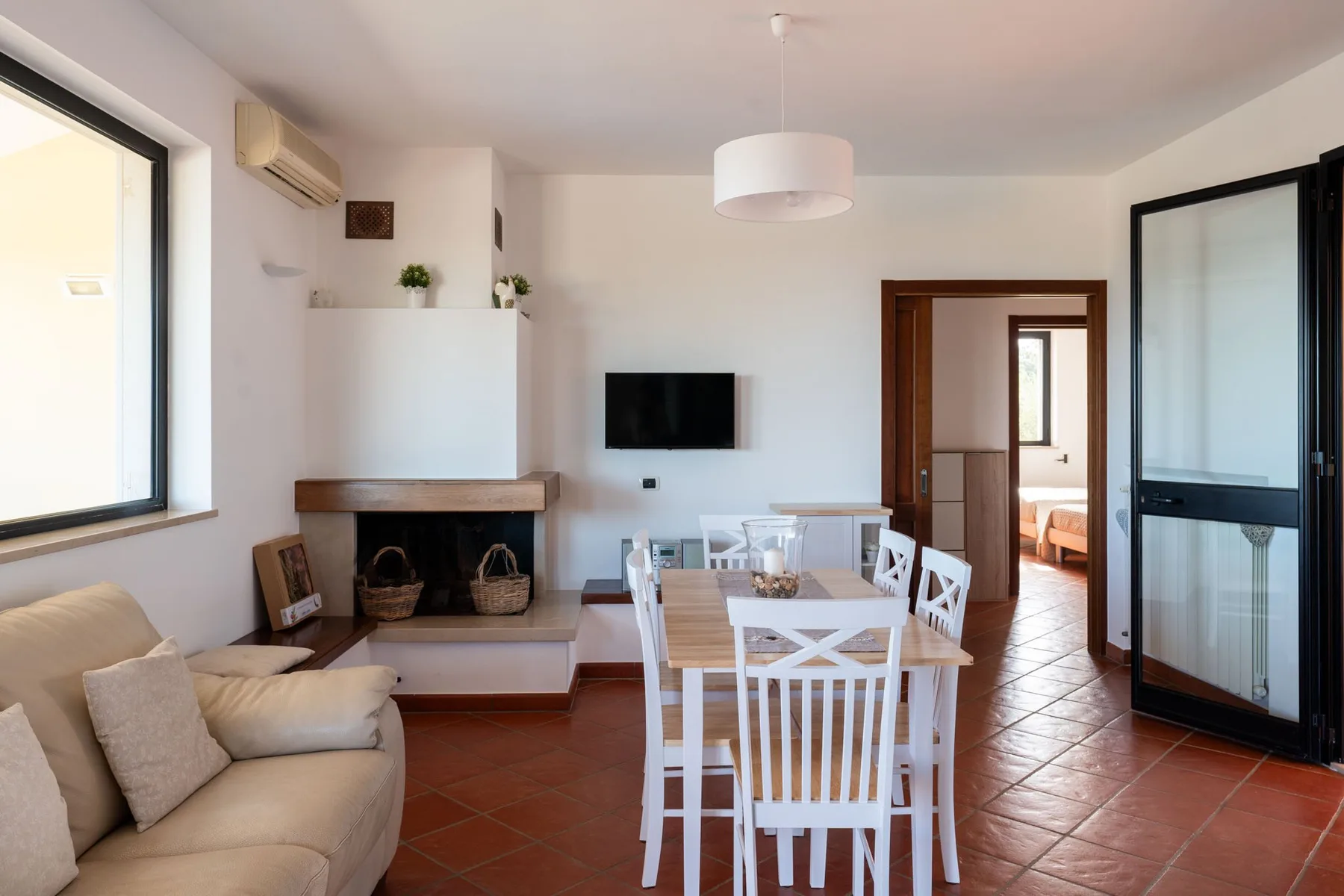 Comedor con mesa y sillas blancas junto a una zona de estar.