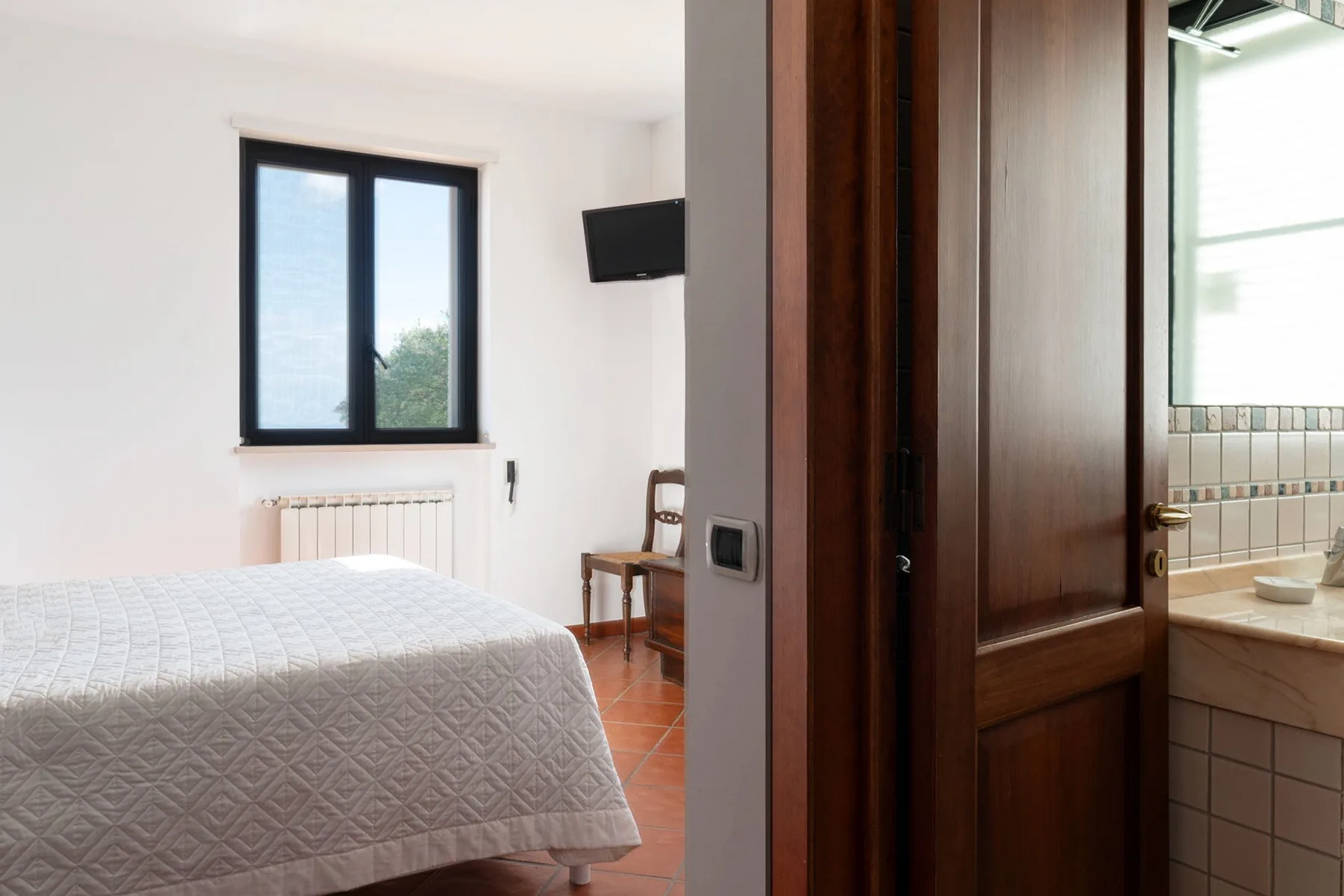 Un dormitorio con una cama, una ventana y vista al baño contiguo.