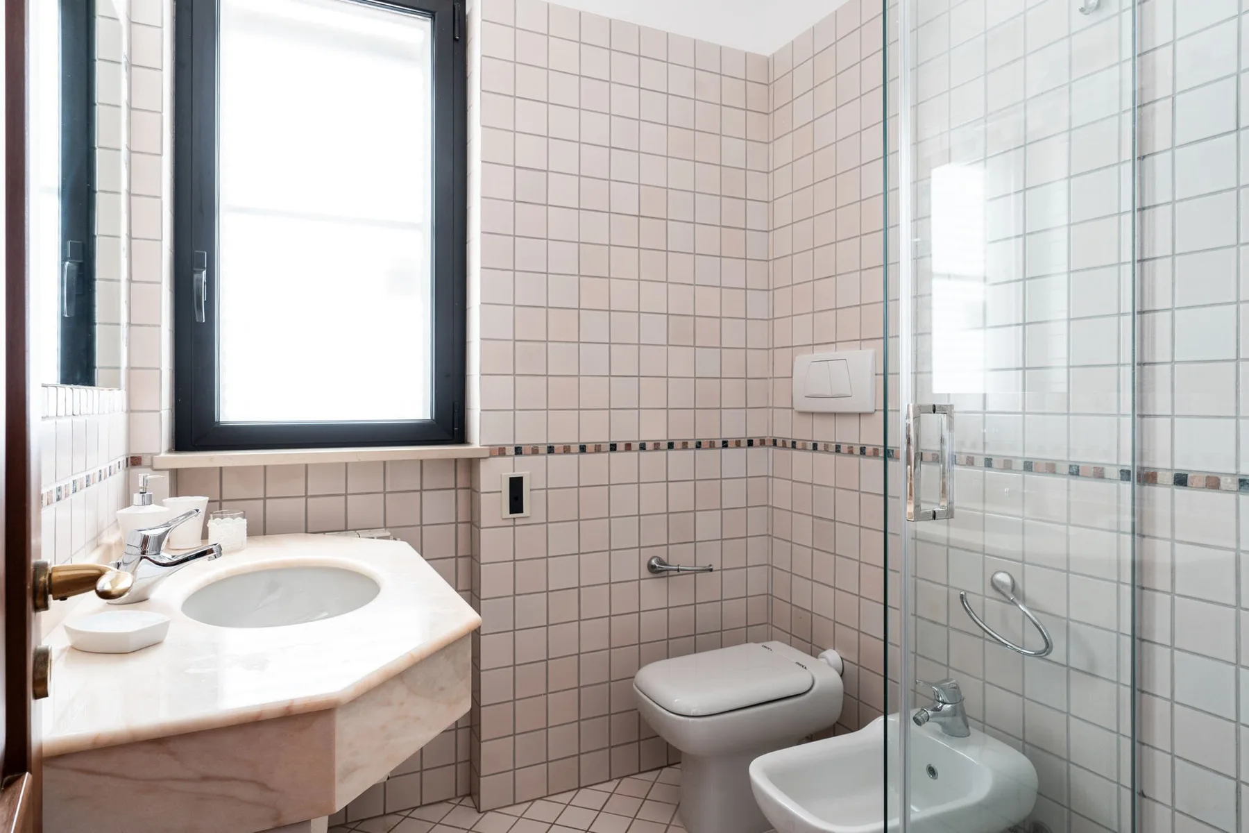 Un baño alicatado con lavabo, inodoro y ducha de vidrio.