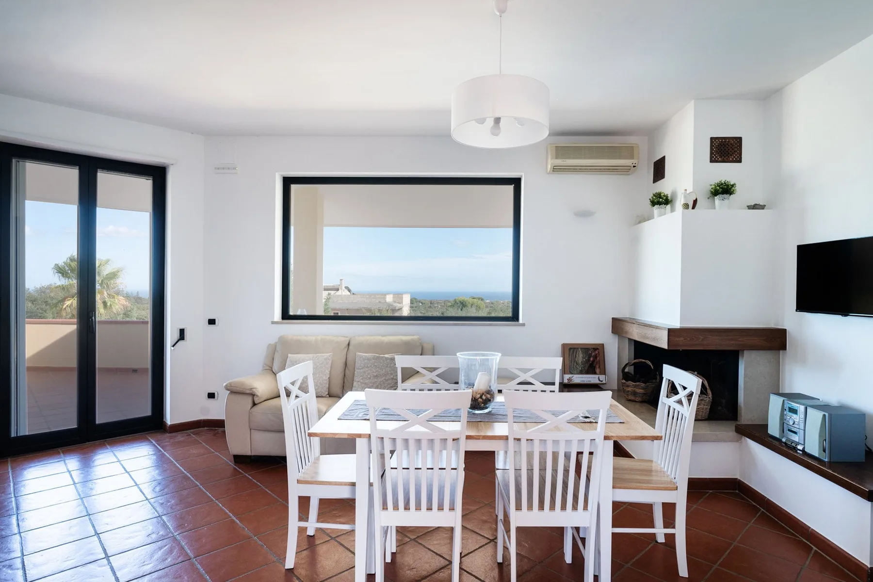 Una luminosa zona de comedor y estar tiene una mesa blanca y vistas al mar.