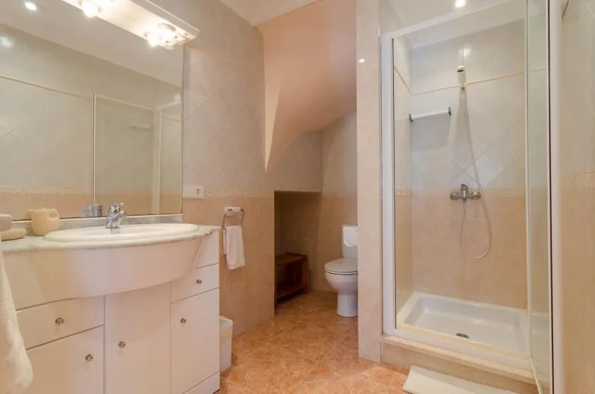 A bathroom with a sink, toilet, and glass-enclosed shower.