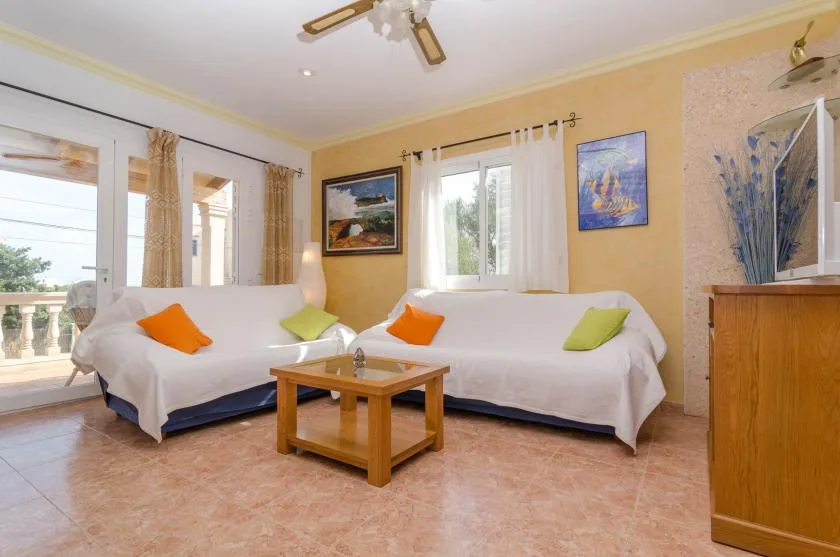 A bright living room with white seating and a wooden coffee table.
