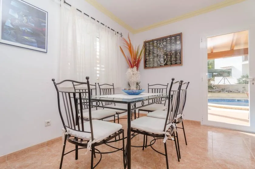A dining area with a glass table and seating beside an open doorway.