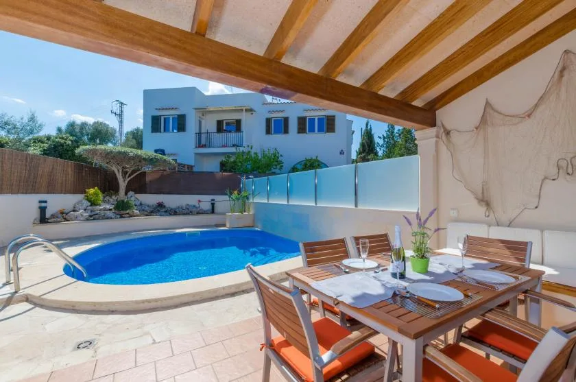 A covered patio dining area overlooks a swimming pool and neighboring buildings.