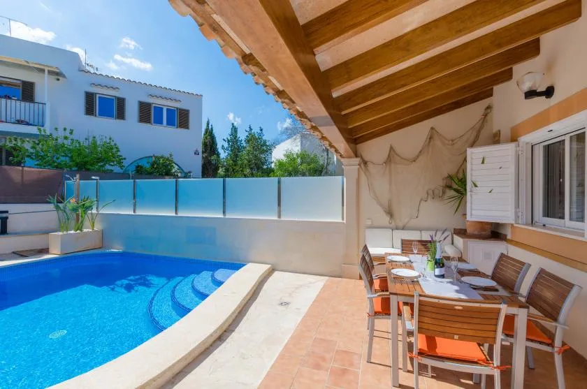 A swimming pool beside a covered outdoor dining area.