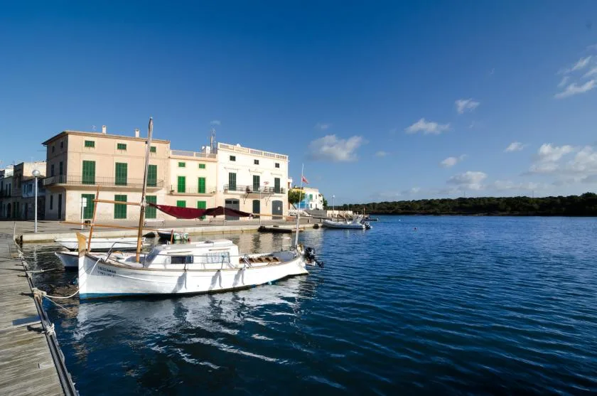 A waterfront harbor with moored boats beside light-colored buildings.