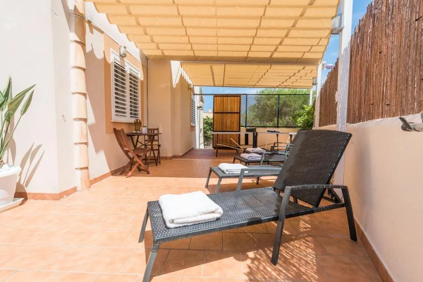 A covered outdoor patio with lounge seating and a small dining table.