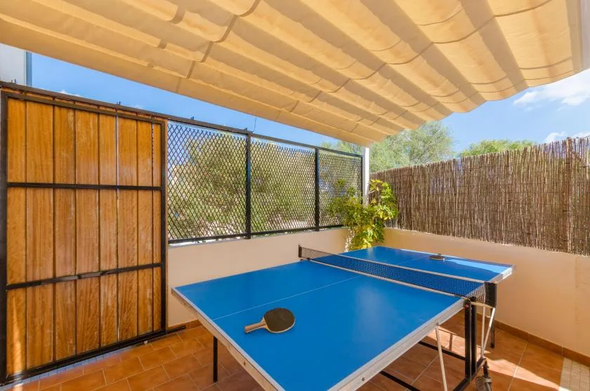 A blue table tennis table sits on a covered outdoor patio.