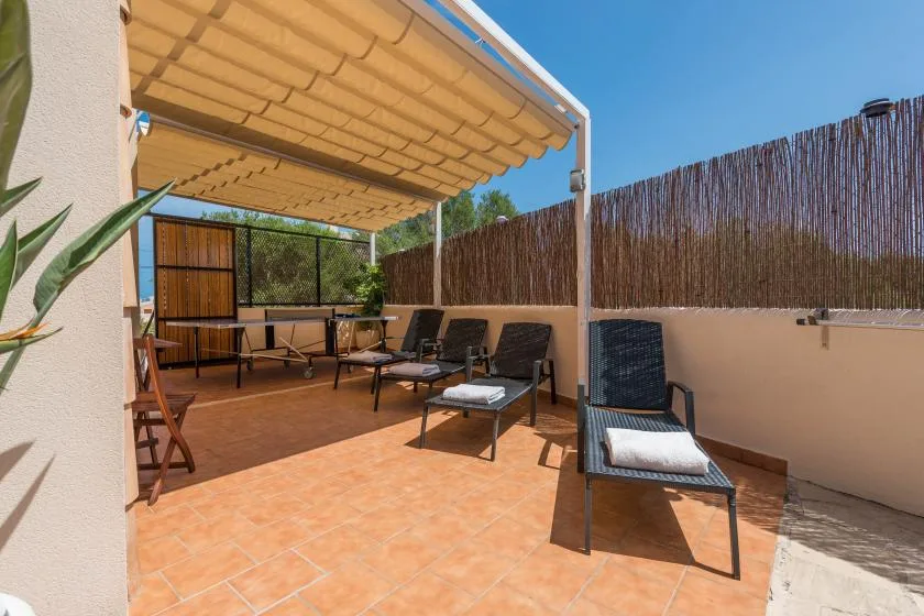 A tiled outdoor terrace with seating beneath a retractable canopy.