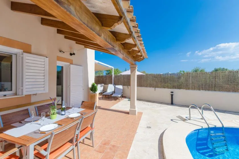 A covered patio with an outdoor dining table beside a swimming pool.