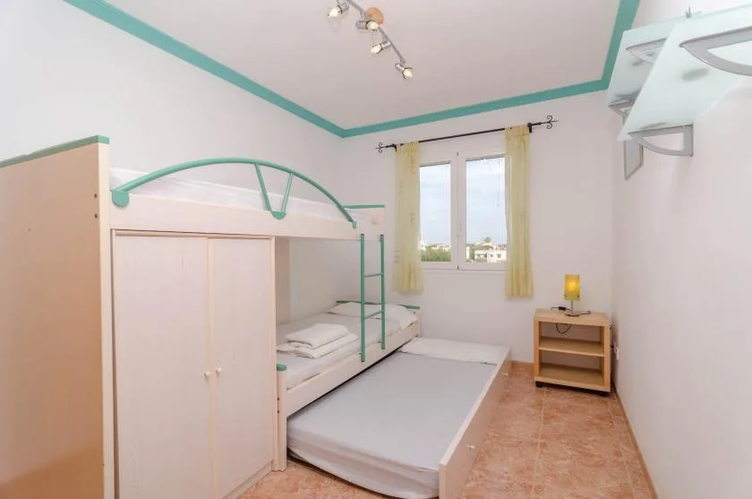 A bedroom with a raised bed, a lower mattress, and a window with curtains.