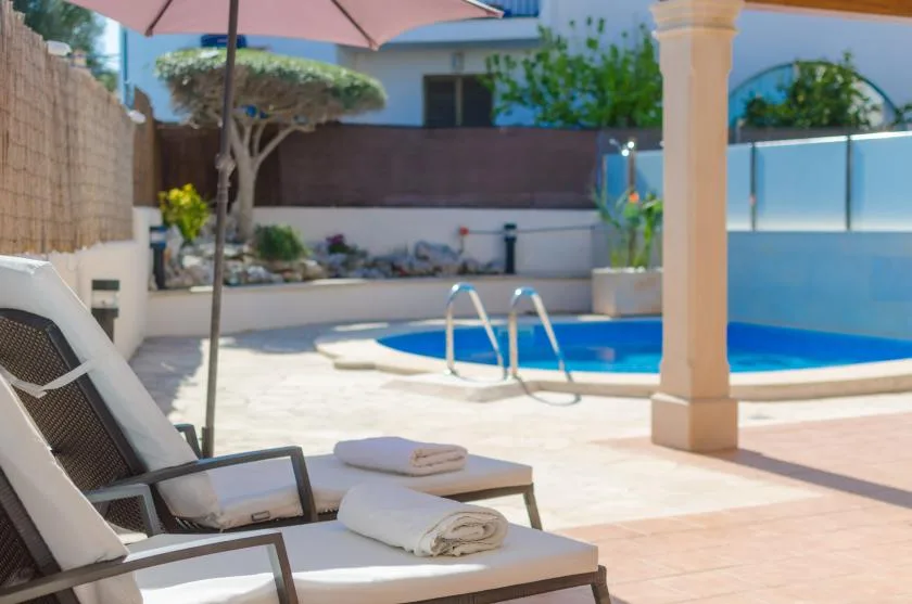 A poolside patio with lounge seating and a large shade umbrella.