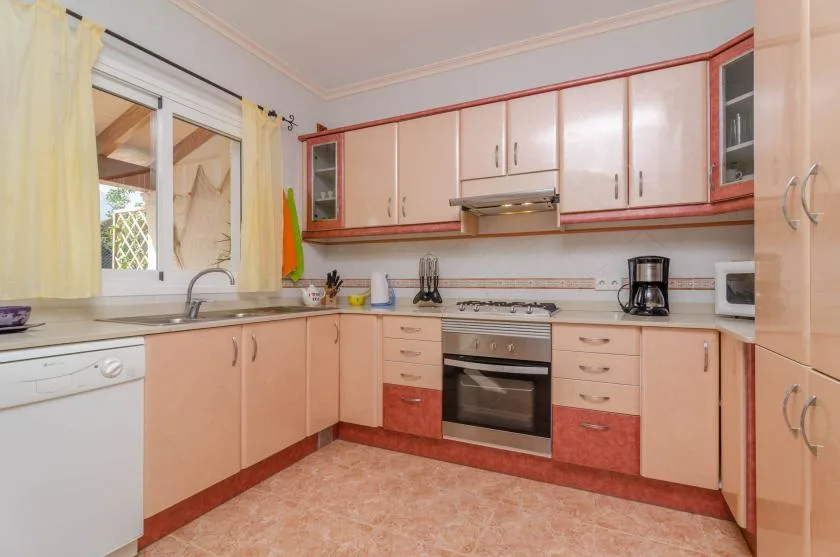 A kitchen with peach-colored cabinets, a countertop, and an oven.
