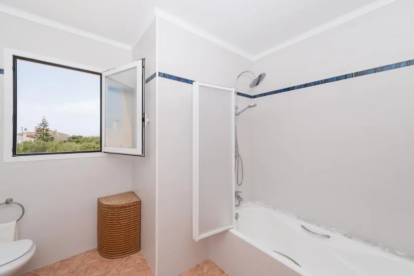 A bathroom with a bathtub, shower, and an open window.