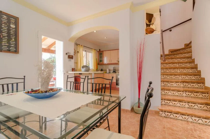 A dining area opens onto a kitchen, with a staircase beside the table.