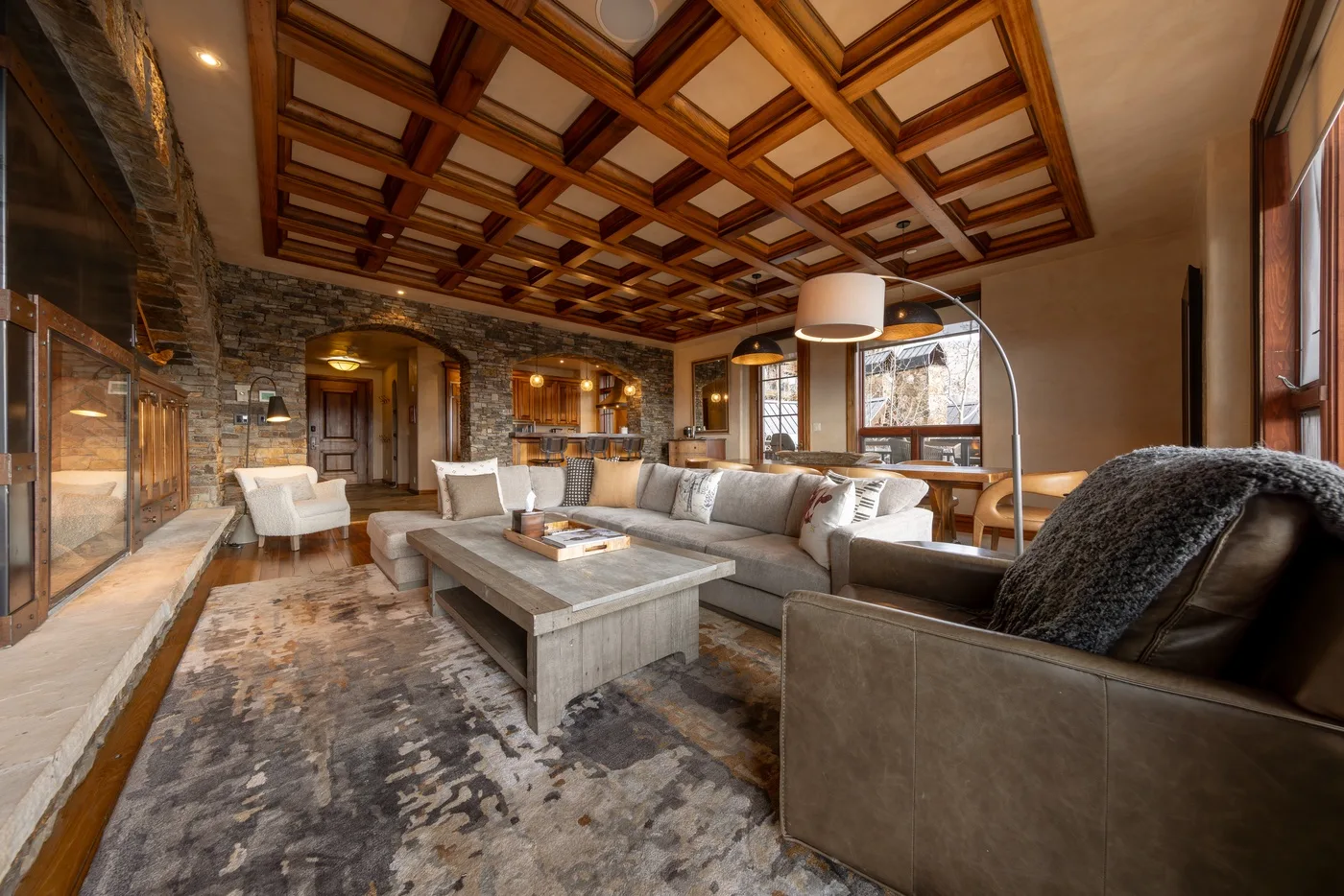 A spacious living room with sectional seating, a coffee table, and a patterned ceiling.
