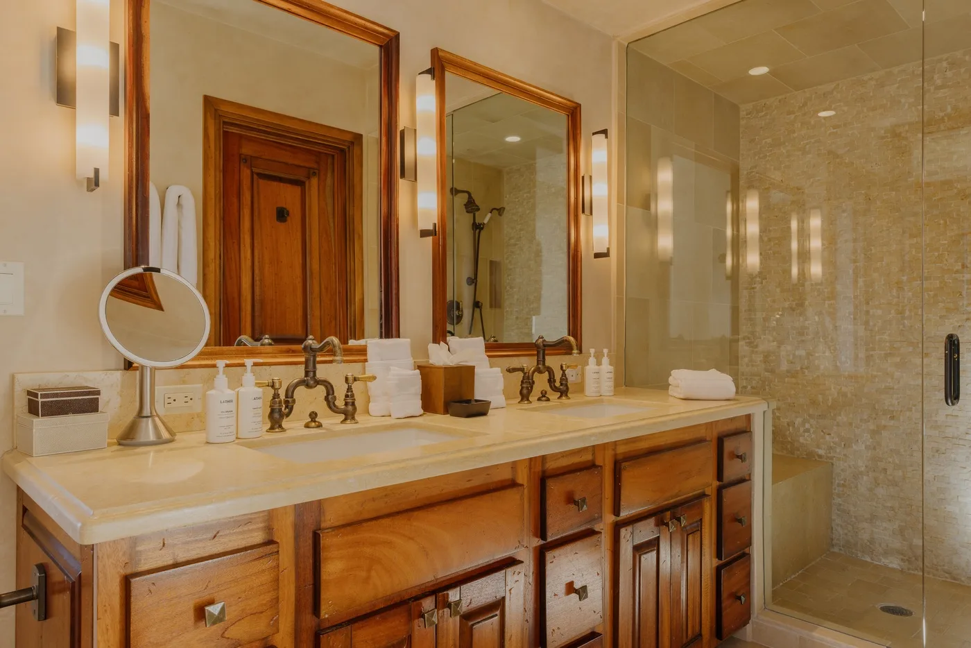 A bathroom vanity with mirrors and a glass shower.