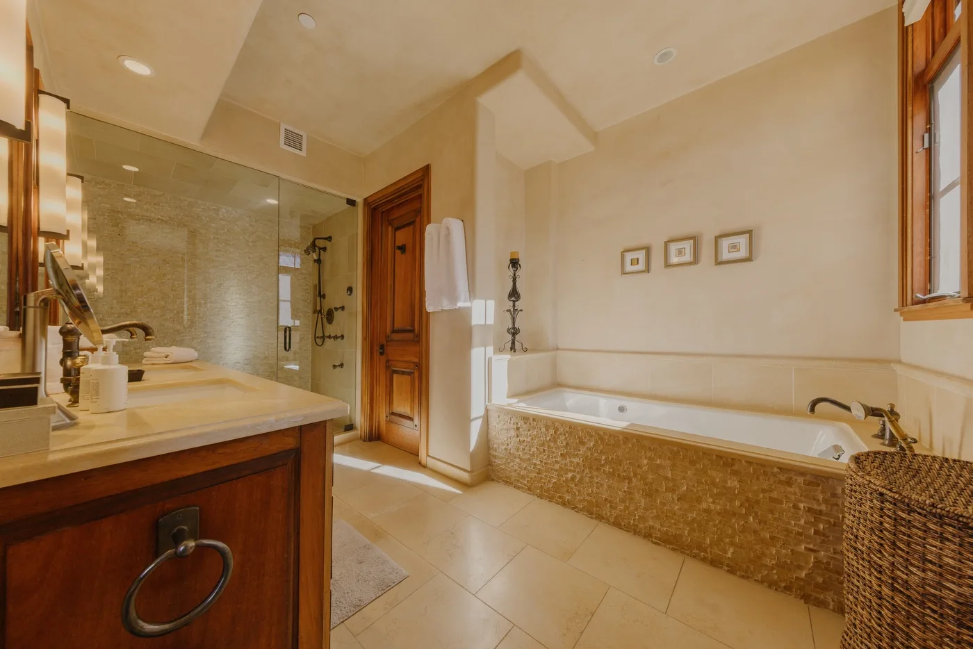 A bathroom with a bathtub, sink, and glass-enclosed shower.