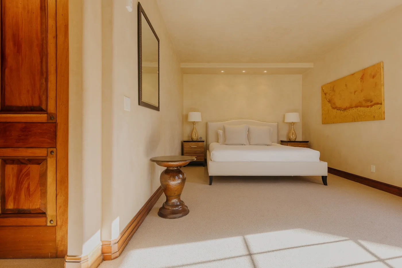 A bedroom with a bed, bedside tables, and warm-toned wall art.