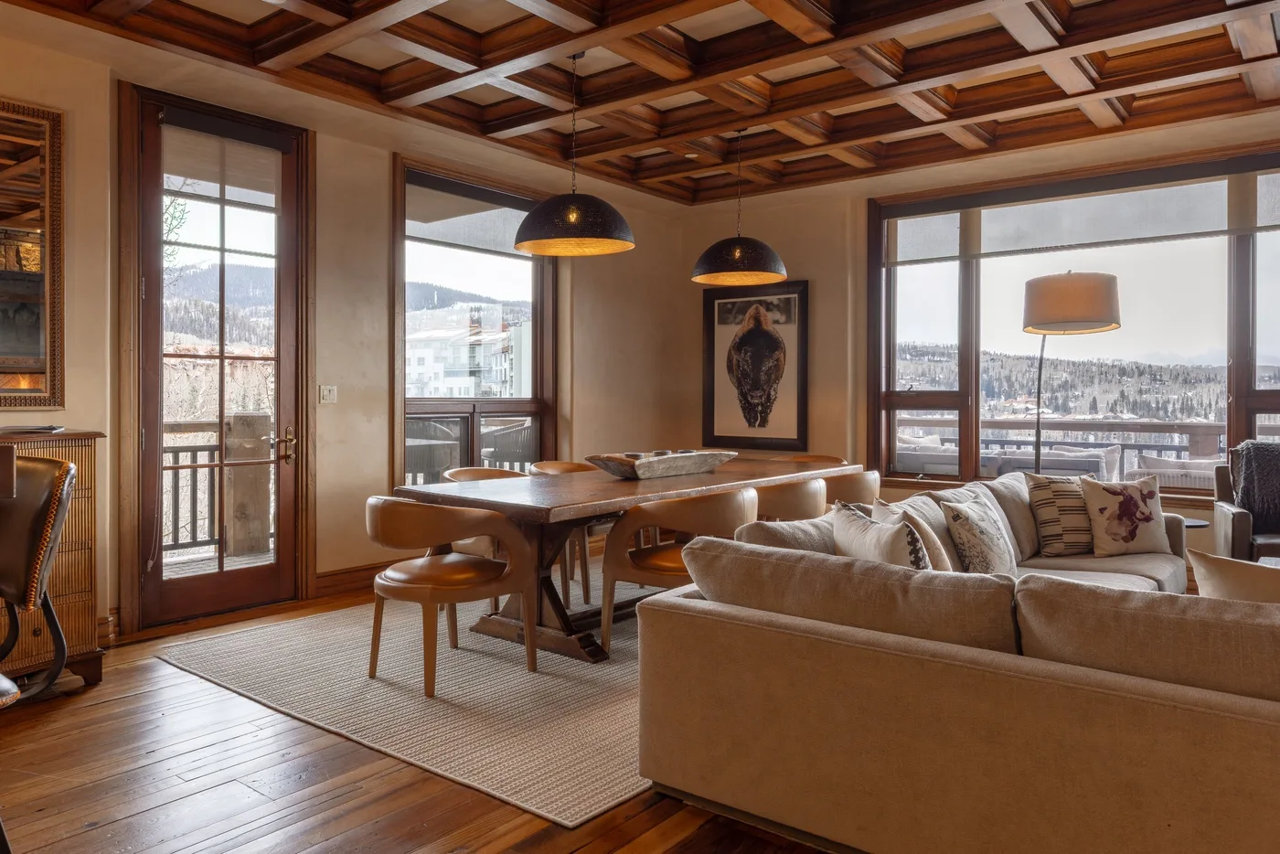 A living and dining area with seating, a dining table, and large windows.