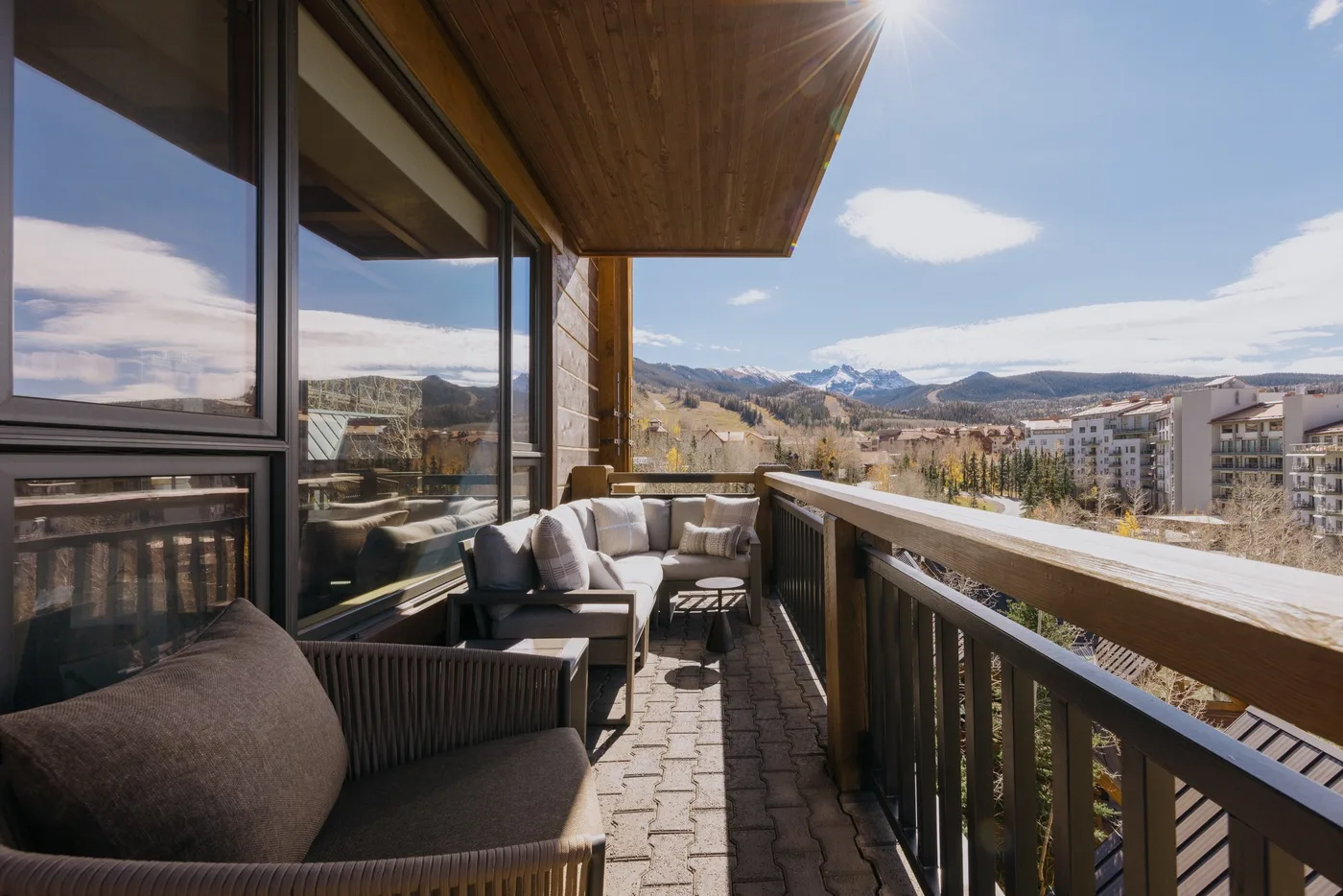A balcony seating area overlooks a town and distant mountains.
