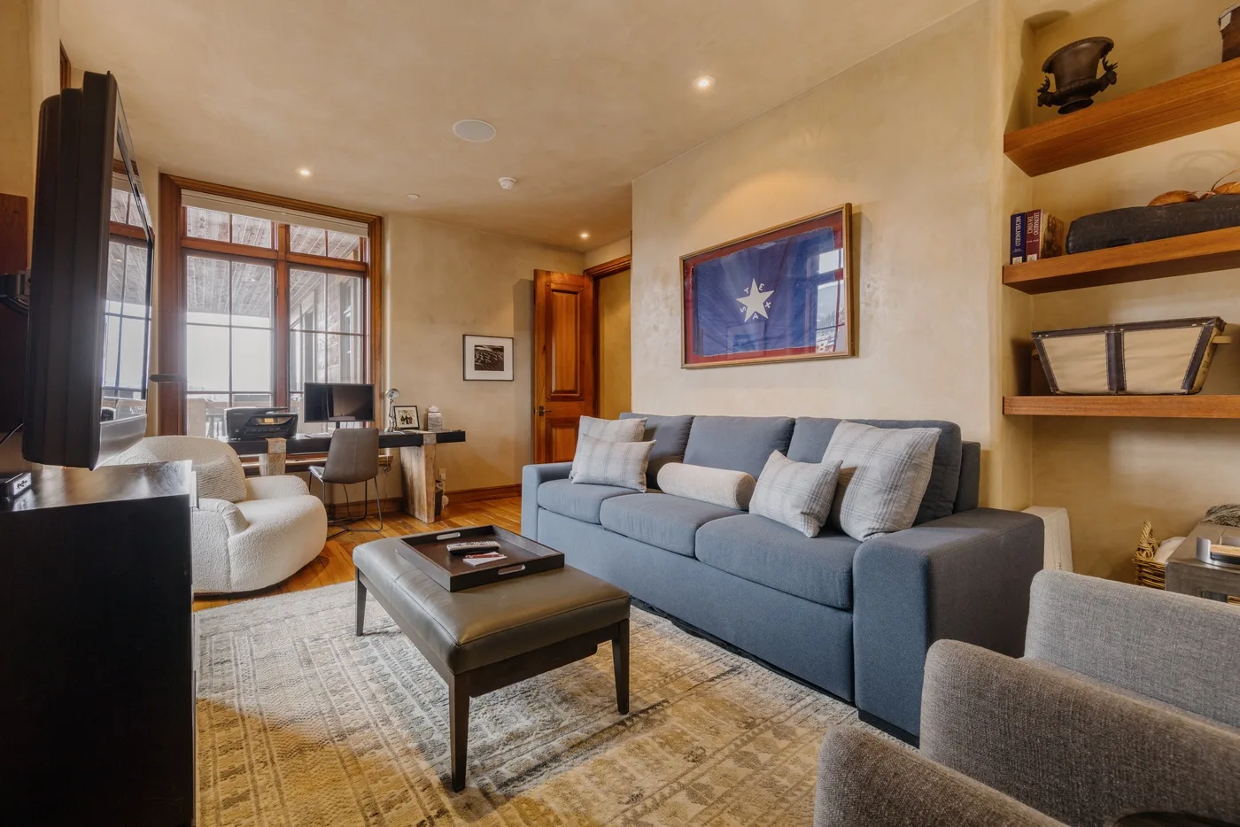 A living room with blue seating, a coffee table, and framed artwork.