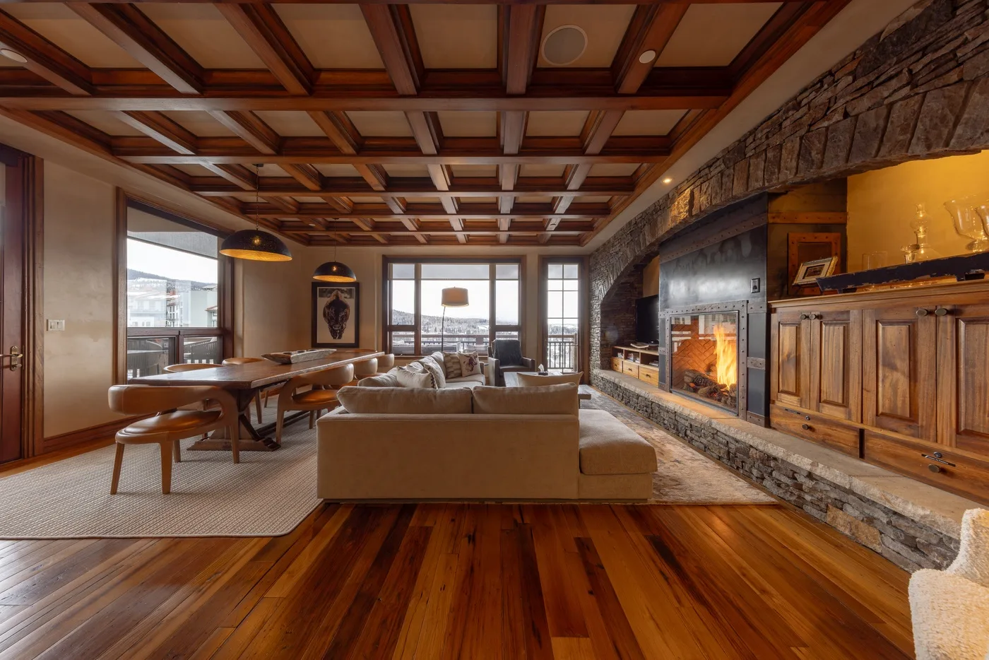 A spacious living room with seating, a dining table, and a stone fireplace.