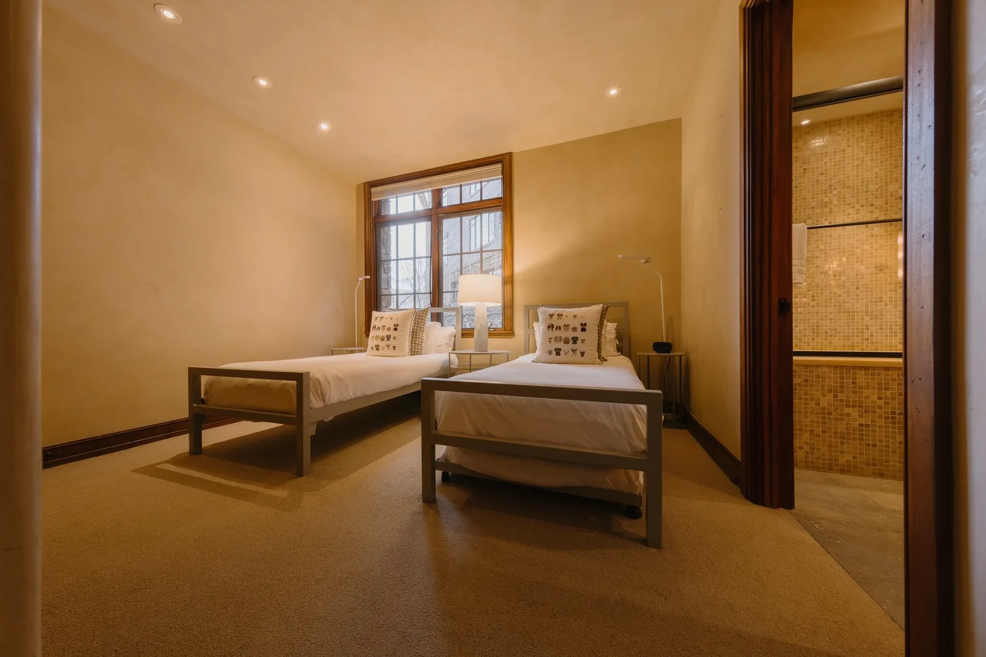 A bedroom with two beds, a window, and a tiled shower area.