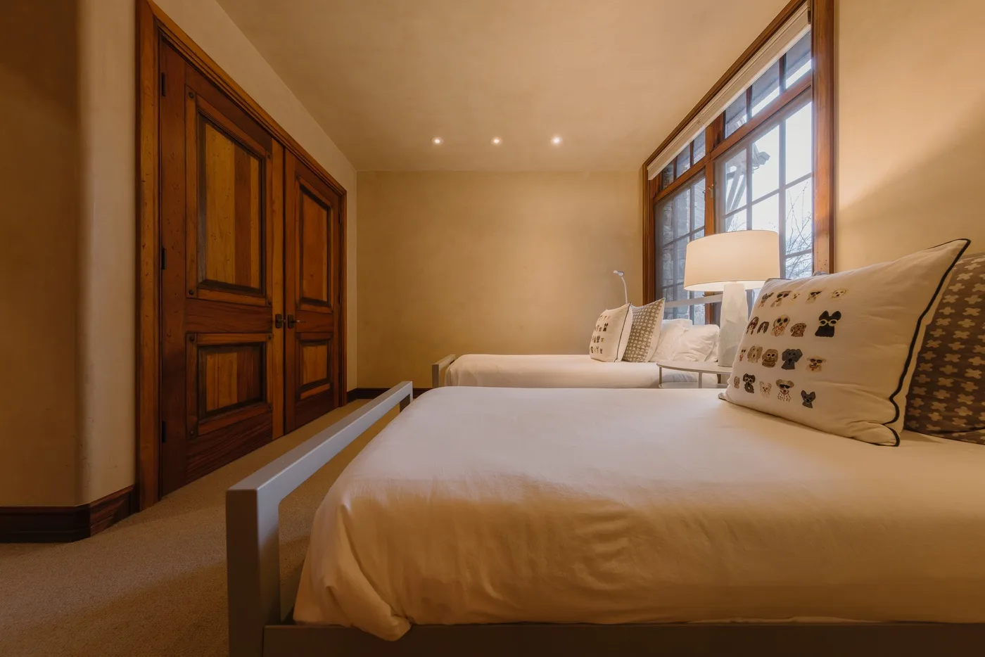 A bedroom with two beds beside a large window.