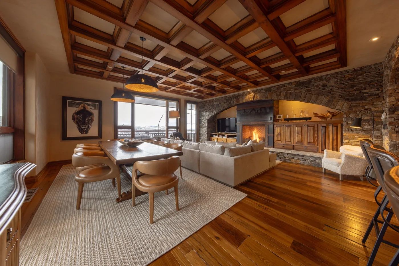 A spacious living and dining area with a fireplace and wood-paneled ceiling.