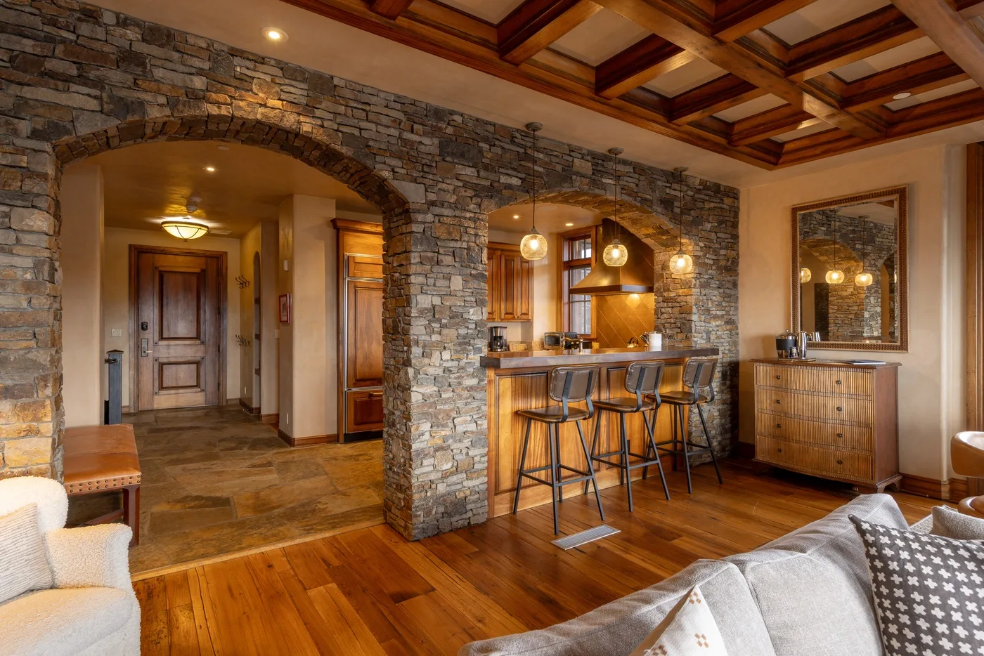 A living area opens onto a stone-arched kitchen with a wooden ceiling.