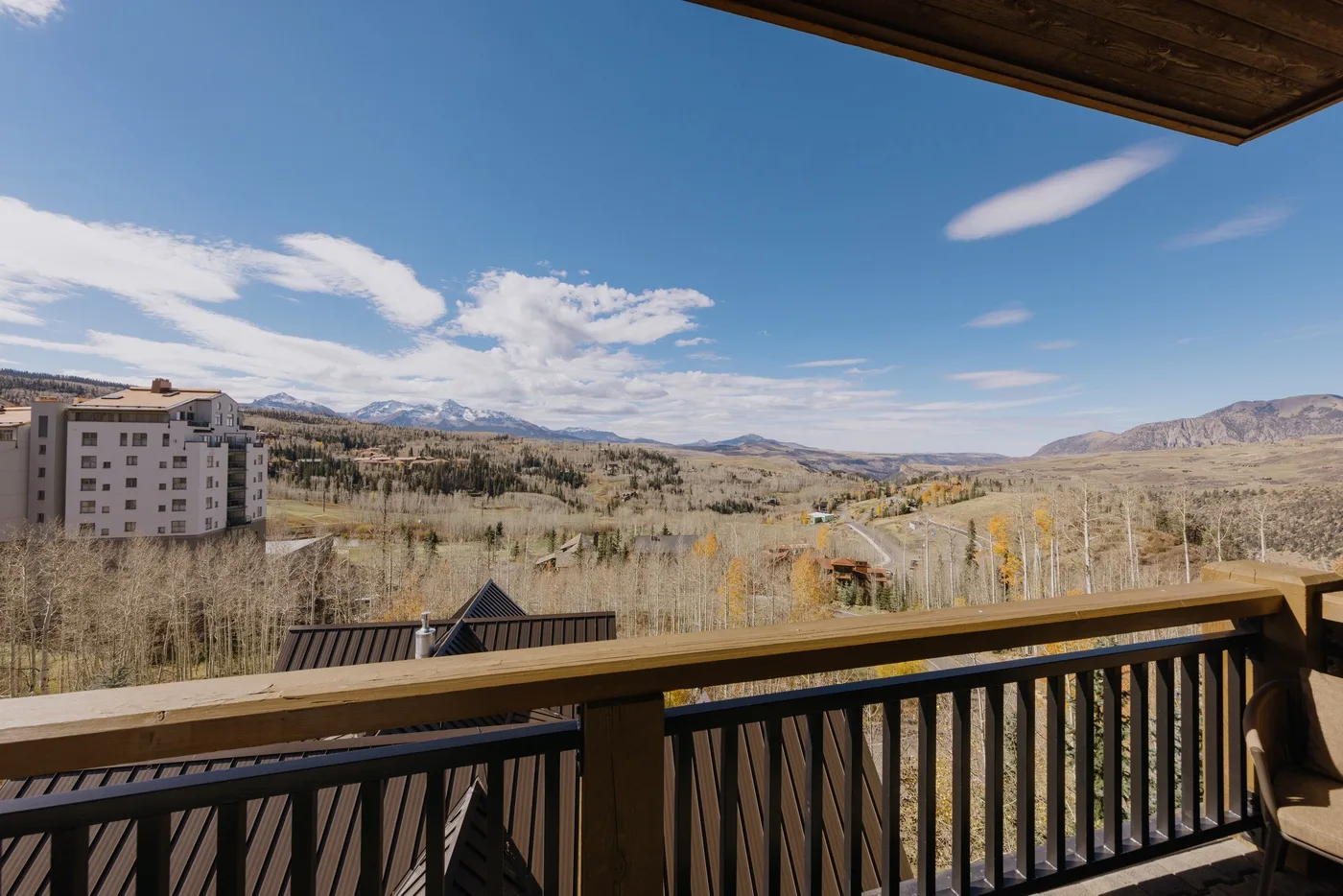 A balcony overlooks a valley with distant mountains and scattered buildings.