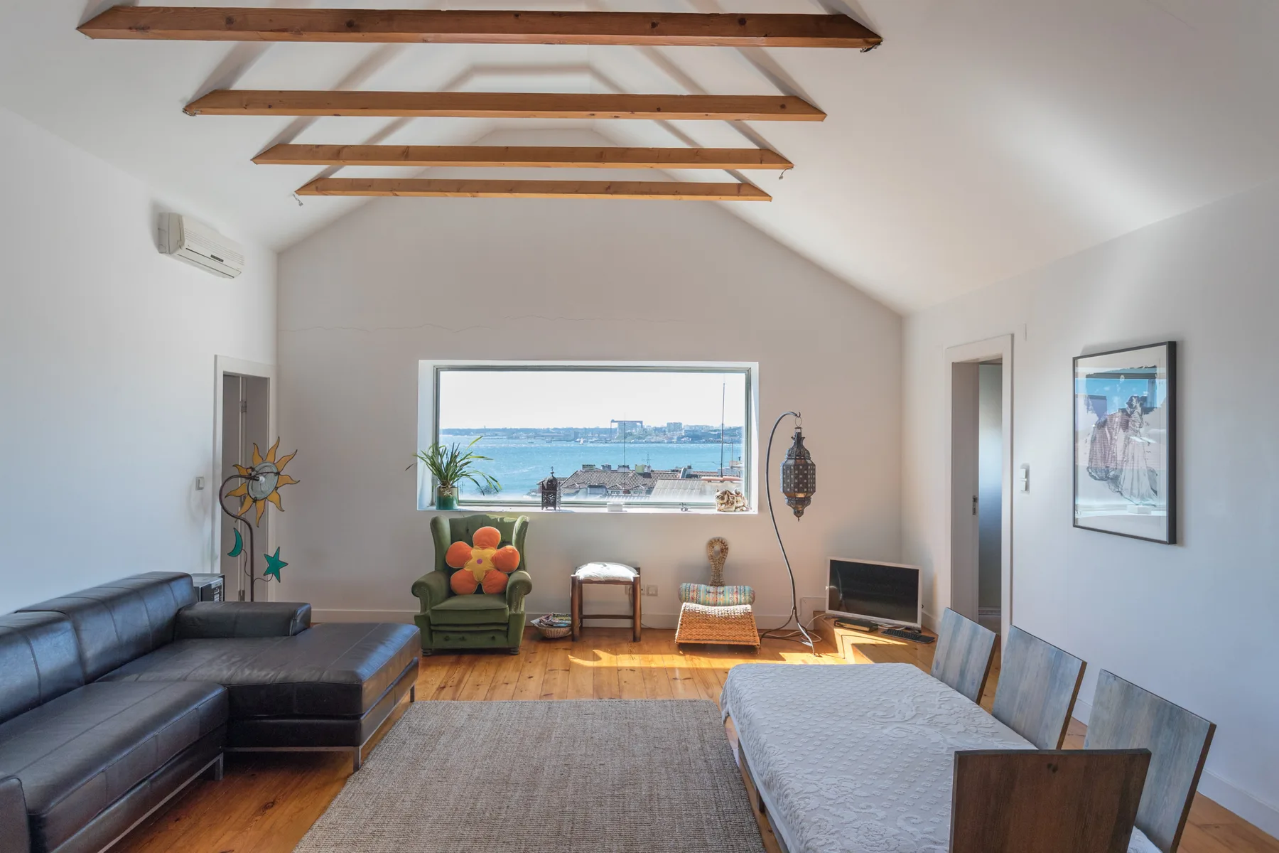 Sala de estar y comedor con asientos, una mesa y una amplia ventana con vistas al agua.