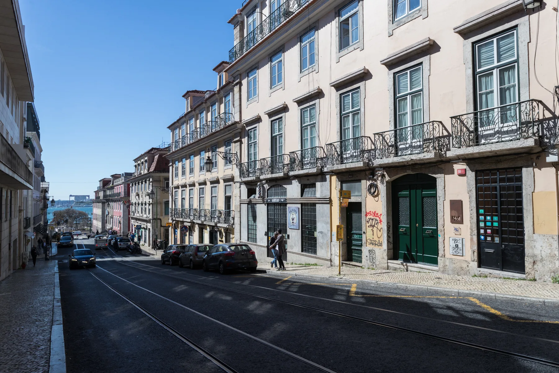 Una calle urbana flanqueada por edificios altos, con vías de tranvía a lo largo de la calzada.
