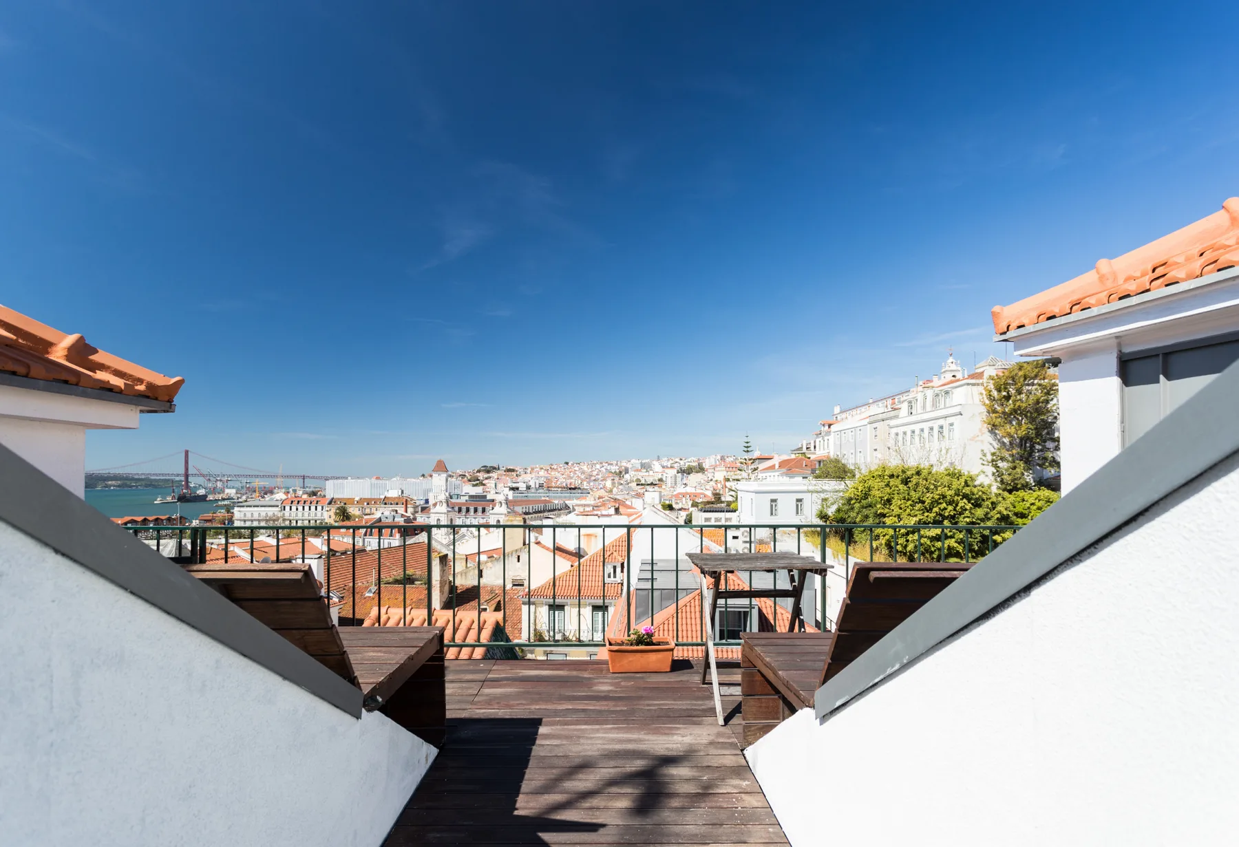 Una terraza en la azotea ofrece vistas del perfil urbano bajo un cielo azul despejado.