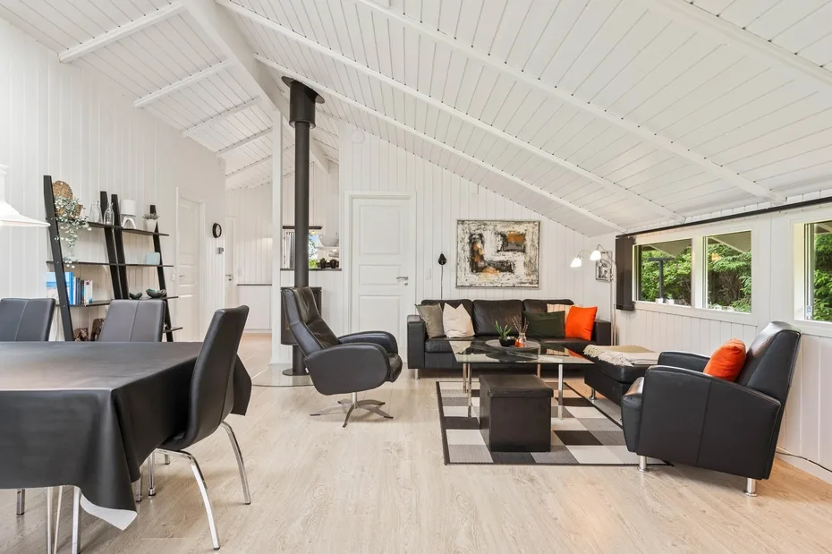 A bright living room with dark seating, a coffee table, and large windows.