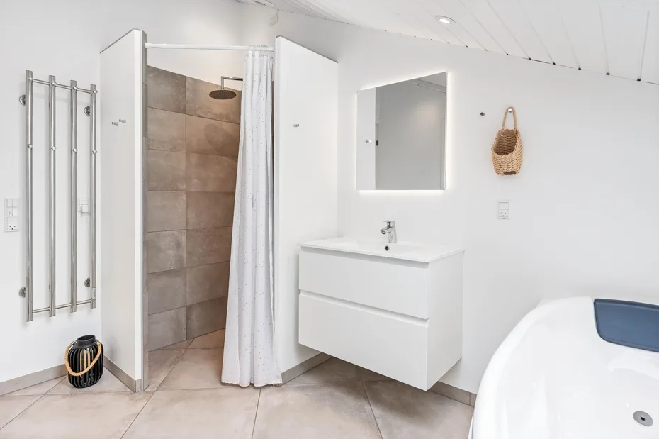 A bright bathroom with a walk-in shower, wall-mounted sink, and bathtub.