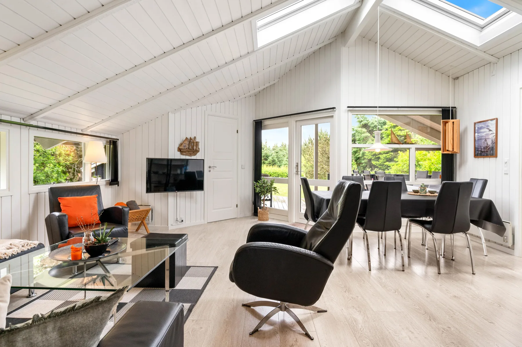 A bright open-plan living and dining area has seating and large windows.