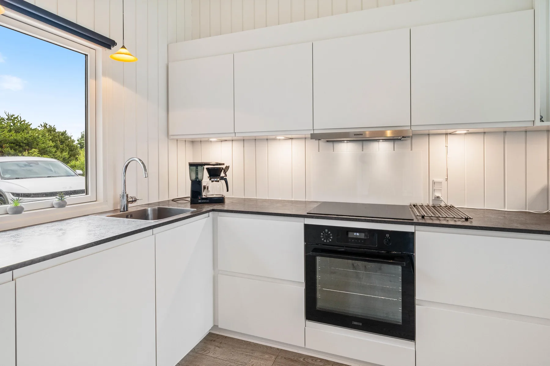 A bright kitchen with white cabinetry, a sink, and an oven.