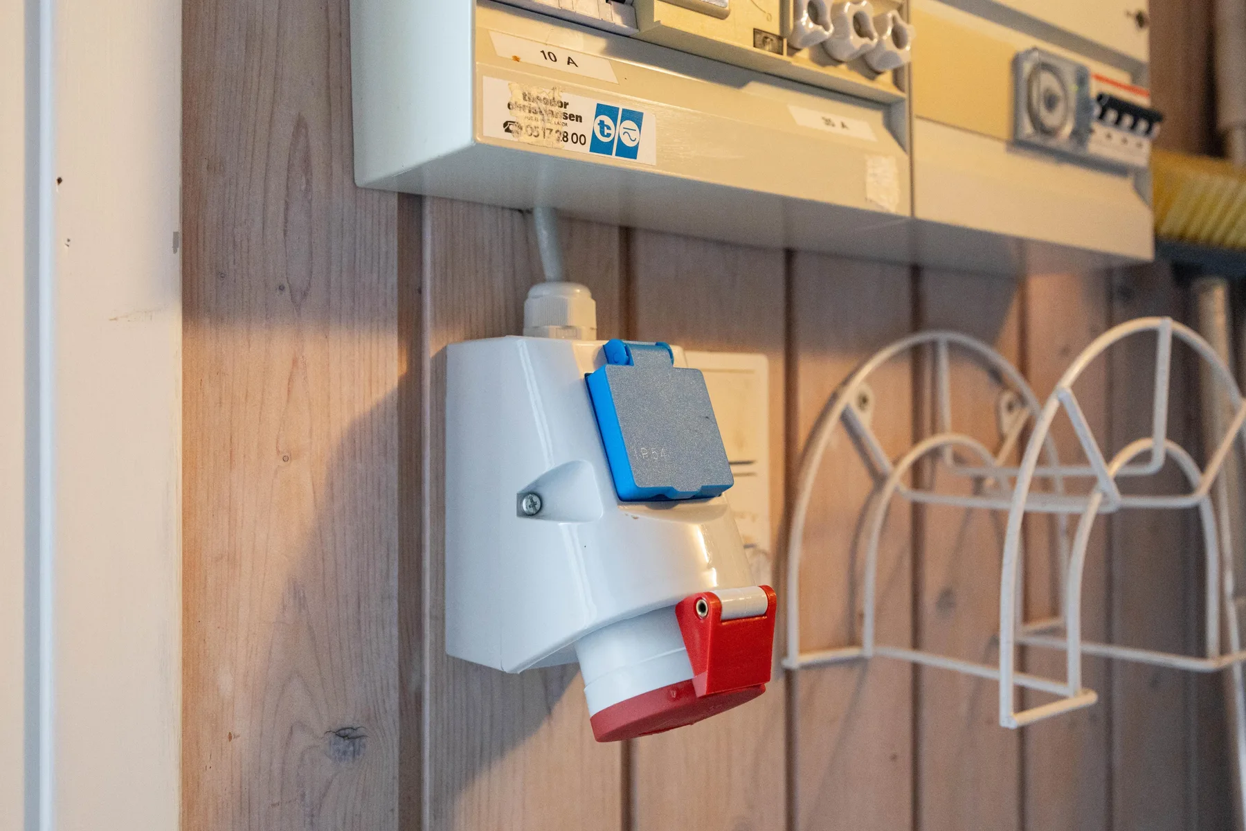 An electrical panel and outlet are mounted on a wood-paneled wall.