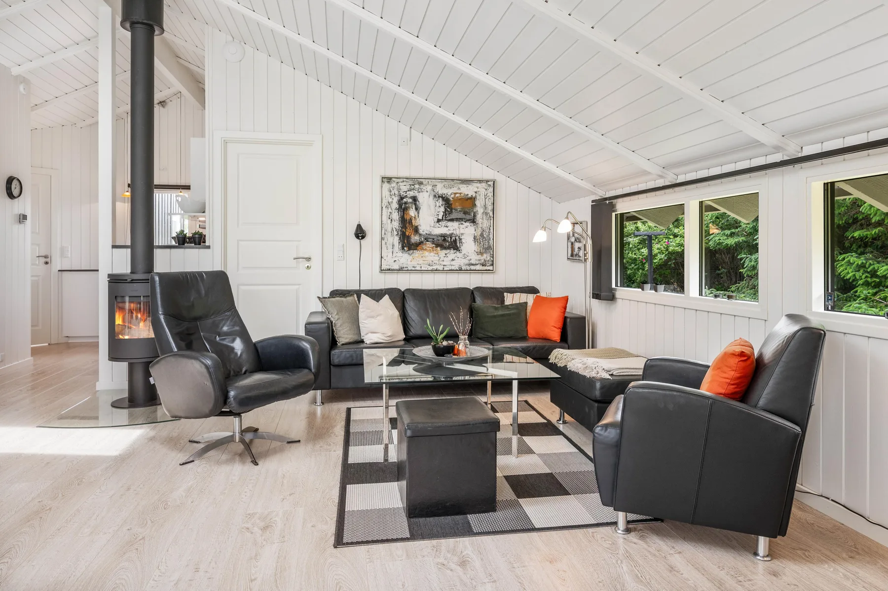 A bright living room with dark seating, a coffee table, and a wood-burning stove.