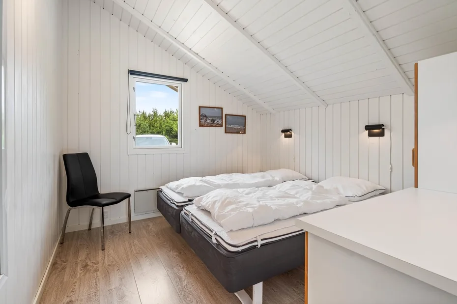 A bedroom with two beds beneath a sloped white ceiling.