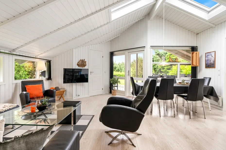 A bright living and dining area with seating, a television, and large windows.