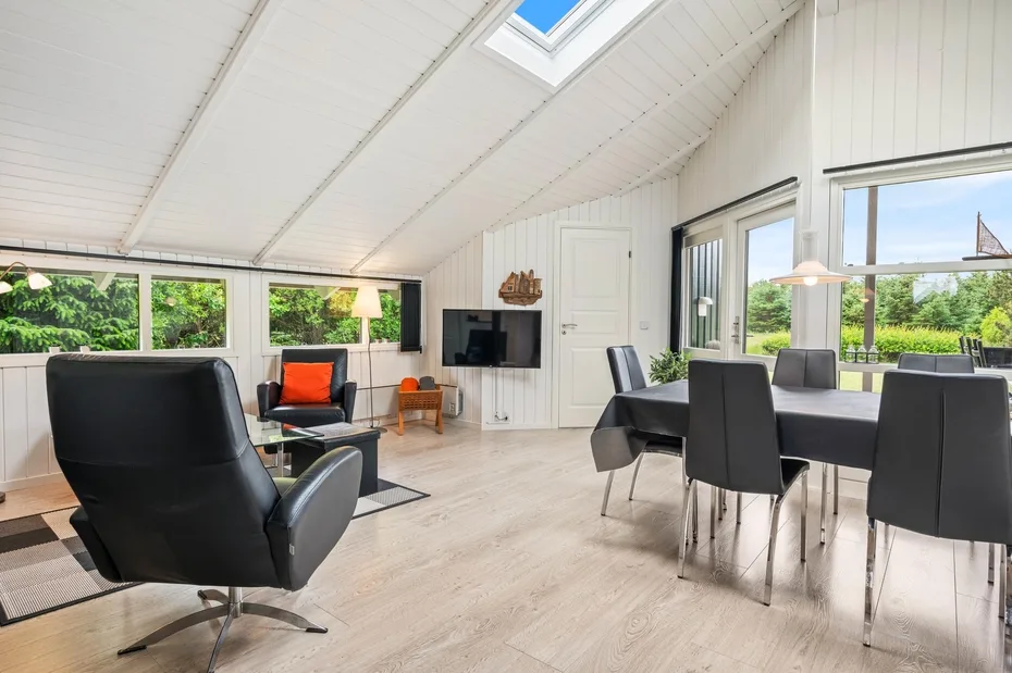 A bright open-plan living and dining area with large windows and a skylight.