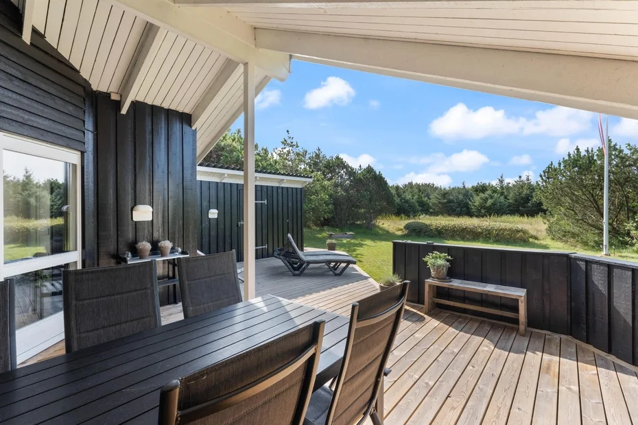 An outdoor deck with seating overlooks a grassy yard and trees.