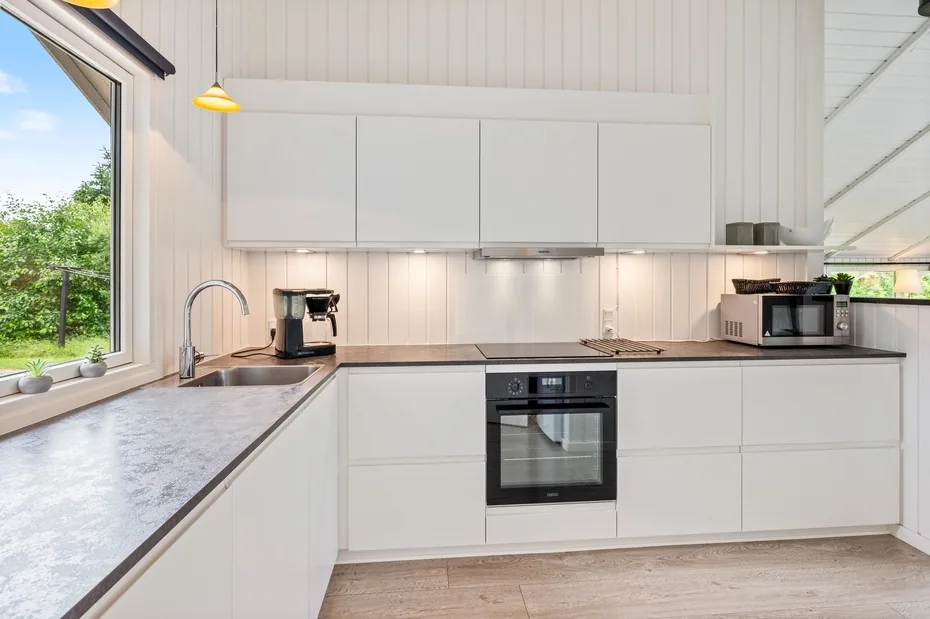 A bright kitchen with white cabinets, a countertop, and an oven.